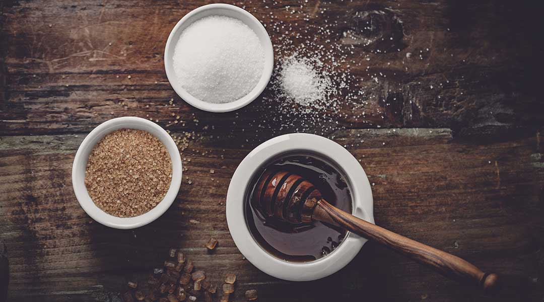 Image of three bowls. One with raw sugar, one with refined sugar, and one with Manuka honey. Manuka honey is a better choice than sugar for individuals with Diabetes